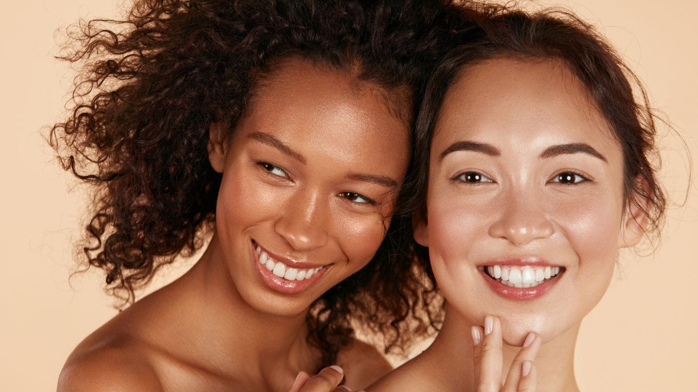 Two women with different hair textures examining their hair - representing low and high porosity hair types