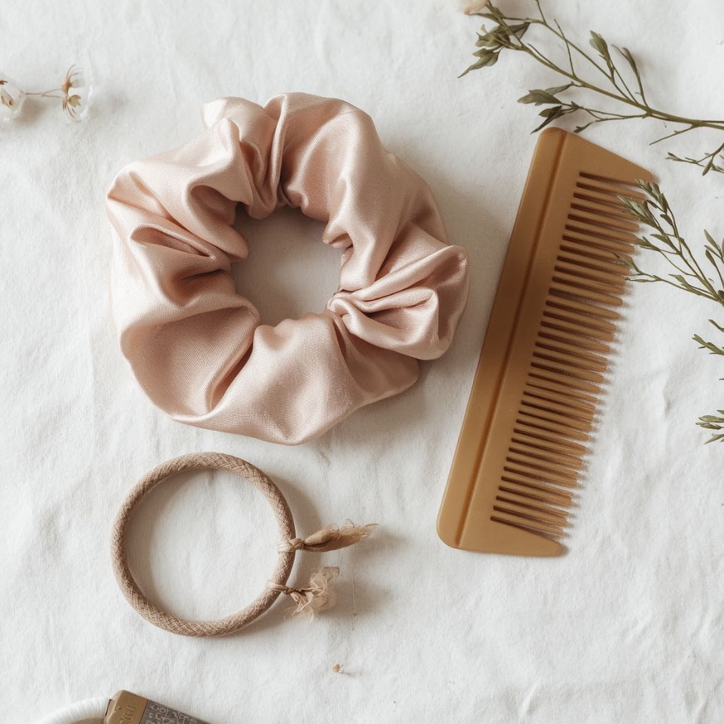 Silk scrunchie and seamless elastics flat lay — gentle hair accessories for workout hairstyles and scalp health